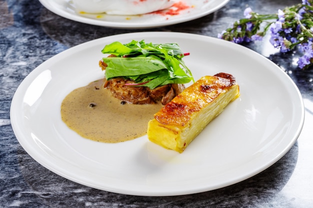 Vue rapprochée sur un gratin de pommes de terre de style parfait avec sauce verte et filet de dinde grillé aux épinards