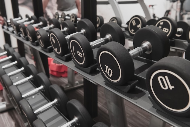 Vue rapprochée d'haltères d'un kilogramme placés sur un porte-haltères au gymnase Equipement d'entraînement au poids