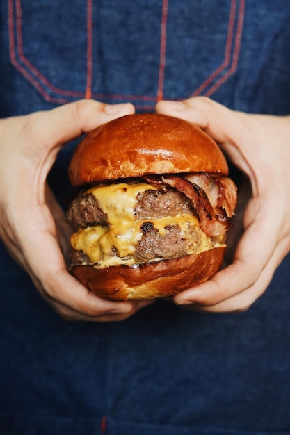 Photo vue rapprochée d'un hamburger tenu à la main