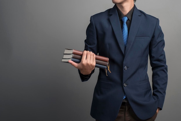 Vue rapprochée d'un homme d'affaires en costume bleu tenant des livres sur fond gris