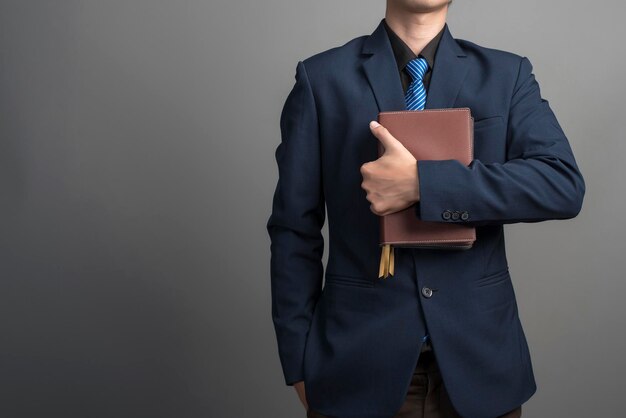 Vue rapprochée d'un homme d'affaires en costume bleu tenant des livres sur fond gris