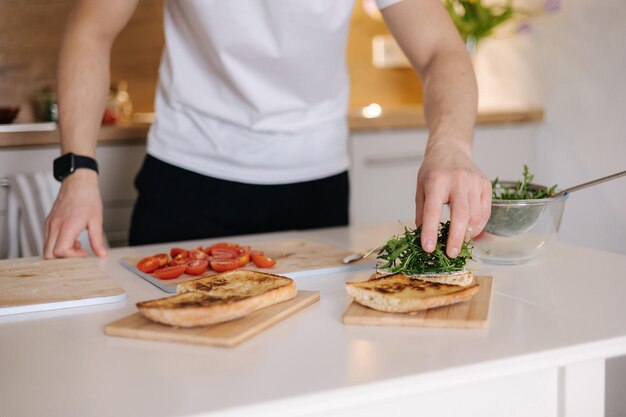 Vue rapprochée d'un homme mettant de l'arugula biologique sur de la nourriture végétalienne bruschetta