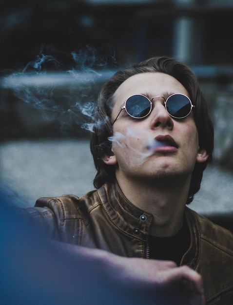 Photo vue rapprochée d'un homme portant des lunettes de soleil exhalant de la fumée