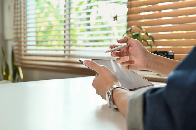 Vue rapprochée d'un homme à la recherche d'informations surfer sur Internet avec une tablette numérique assis à un bureau de travail dans son bureau à domicile