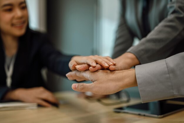 Vue rapprochée des hommes d'affaires s'accrochant les mains pour motiver ou célébrer leur unité au bureau