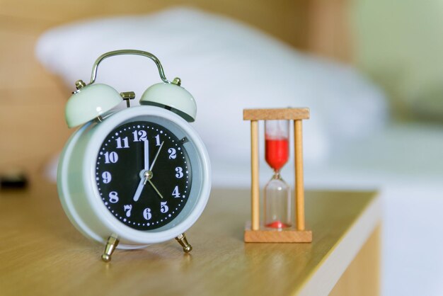 Photo vue rapprochée de l'horloge et du sablier sur la table de la chambre.