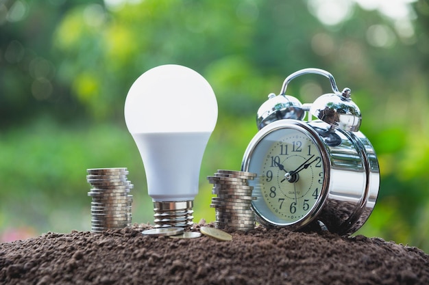 Photo vue rapprochée de l'horloge de réveil par pile de pièces et ampoule led sur la boue