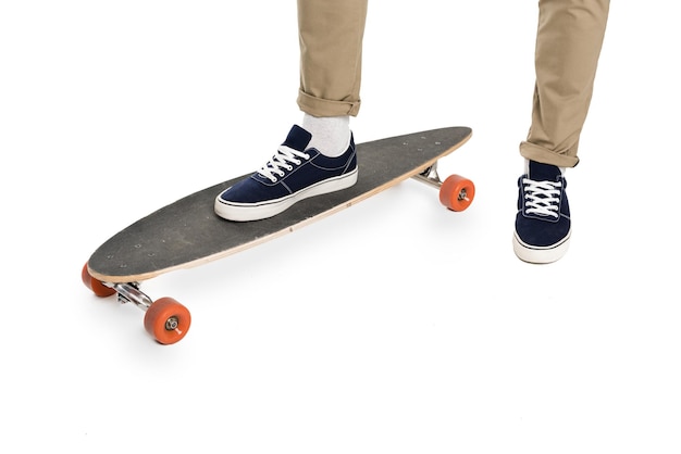 Vue rapprochée des jambes masculines dans des chaussures élégantes et longboard isolé sur blanc