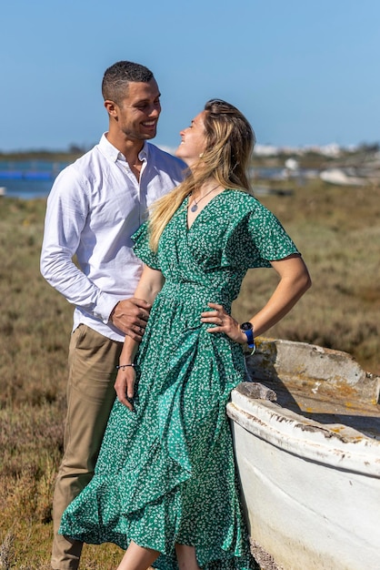Vue rapprochée d'un jeune couple européen heureux tenant ensemble à côté d'un bateau en bois