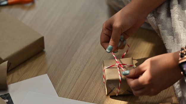 Vue rapprochée de la jeune femme emballant des cadeaux de Noël dans le salon.