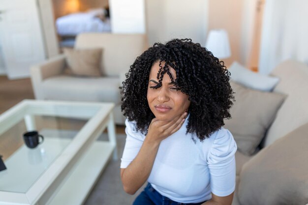 Vue rapprochée d'une jeune femme se frotter les amygdales enflammées problème d'amygdite coupé femme avec un problème de glande thyroïde touchant son cou fille a un mal de gorge