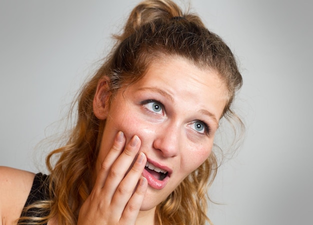 Photo vue rapprochée d'une jeune femme souffrant de maux de dents sur un fond gris