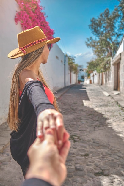 Vue rapprochée d'une jeune femme tenant l'homme par la main tout en le conduisant dans la vieille rue d'Arequipa, au Pérou.