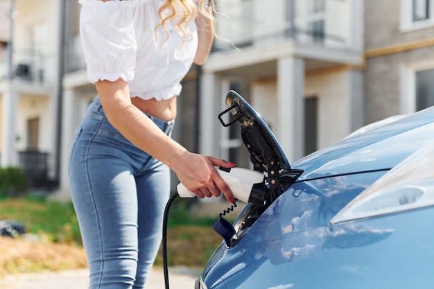 Vue rapprochée Jeune femme en vêtements décontractés avec son électromobile à l'extérieur pendant la journée