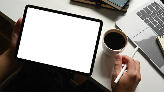 Vue rapprochée d'un jeune homme à l'aide d'une tablette numérique avec un écran de maquette vide vide au bureau de travail blanc