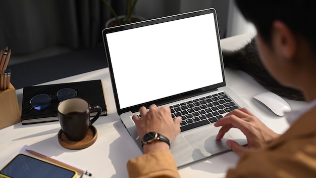 Vue rapprochée d'un jeune homme indépendant utilisant un ordinateur portable à la recherche d'informations sur un lieu de travail confortable.