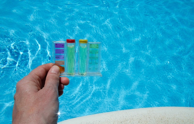 Photo vue rapprochée d'un kit d'essai tenu à la main au-dessus d'une piscine