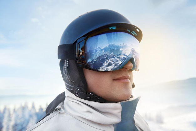 Vue rapprochée des lunettes de ski d'un homme avec le reflet des montagnes enneigées homme en arrière-plan ciel bleu sports d'hiver
