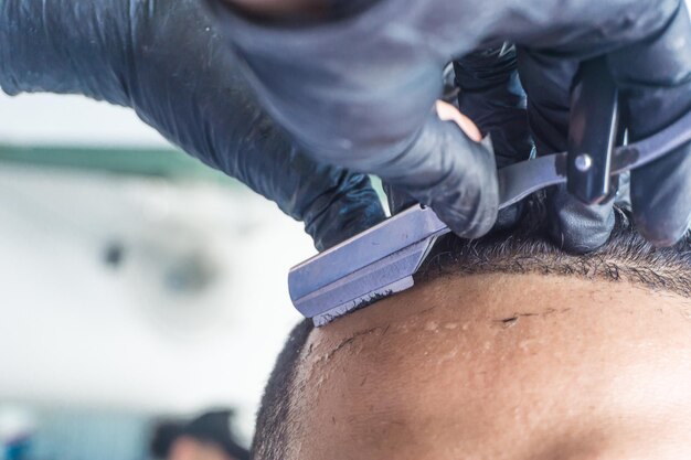 Photo vue rapprochée de la main d'un coiffeur coupant les cheveux d'un client avec un rasoir