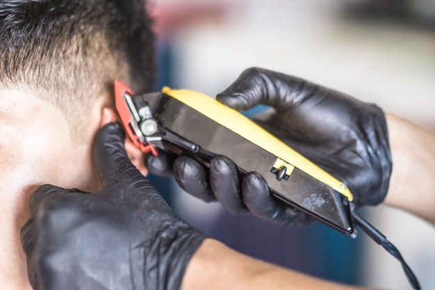 Vue rapprochée de la main d'un coiffeur coupant les cheveux d'un client