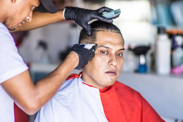 Vue rapprochée de la main d'un coiffeur latin coupant les cheveux d'un client