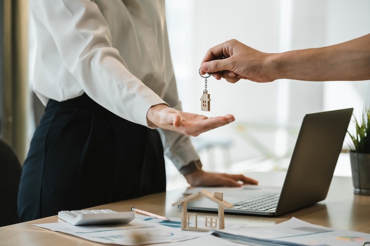 Photo vue rapprochée de la main du propriétaire de l'agent immobilier donnant une maison clé au locataire de l'acheteur dans un bureau moderne.