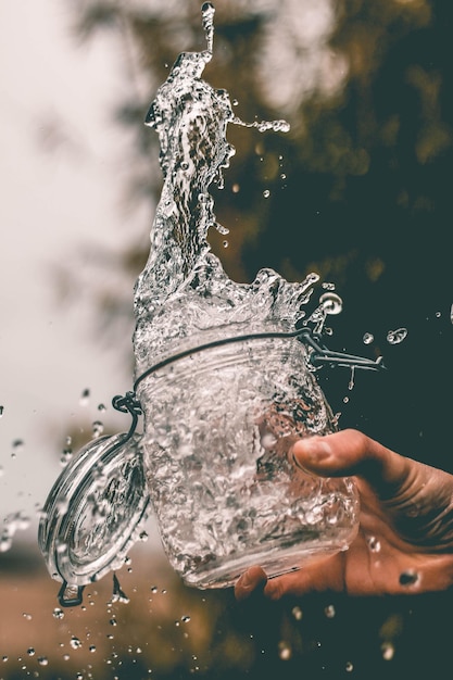 Vue rapprochée d'une main éclaboussant de l'eau à travers un pot