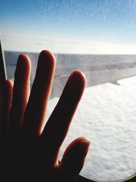 Photo vue rapprochée d'une main sur une fenêtre en verre d'un avion