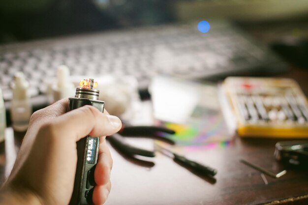 Vue rapprochée d'une main tenant une cigarette électronique sur la table
