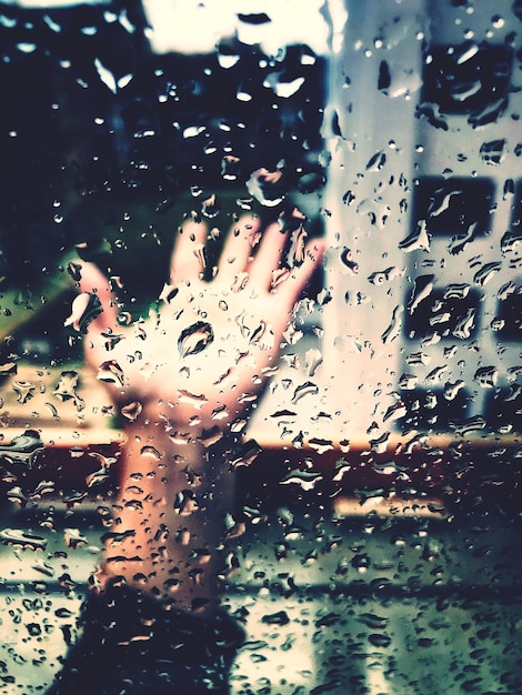 Photo vue rapprochée de la main à travers une fenêtre humide pendant la saison des pluies