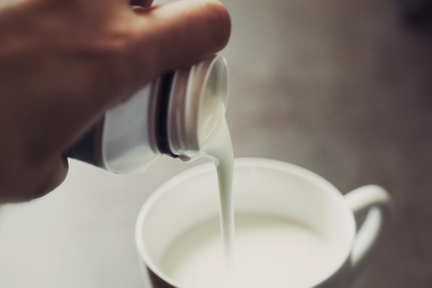 Photo vue rapprochée de la main versant du lait dans une tasse