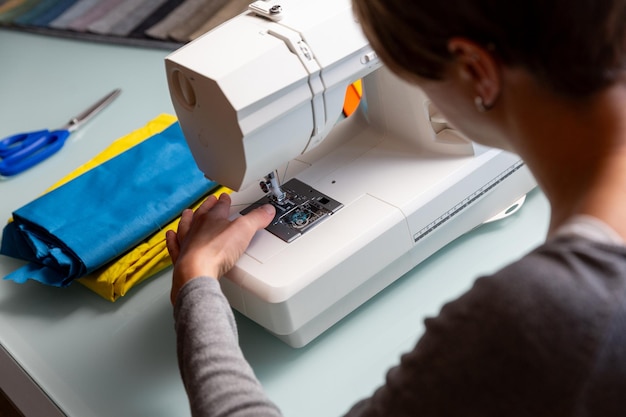 Vue rapprochée des mains féminines du tailleur préparant des échantillons de tissu de machine à coudre inclus