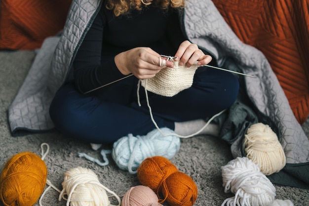 Vue rapprochée des mains d'une femme tricotant une écharpe avec des motifs à l'aide d'aiguilles se relaxant à la maison tout en faisant son activité de passe-temps préférée Concept de style de vie des gens