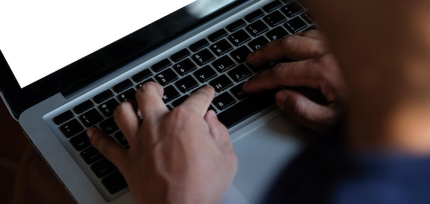 Vue rapprochée des mains de l'homme tapant sur le clavier de l'ordinateur portable