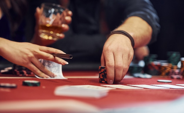 Vue rapprochée des mains des jeunes élégants qui jouent au poker au casino