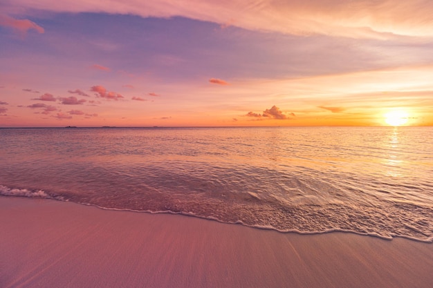 Vue rapprochée majestueuse des vagues d'eau de mer calme avec la lumière du soleil orange au coucher du soleil. Île tropicale