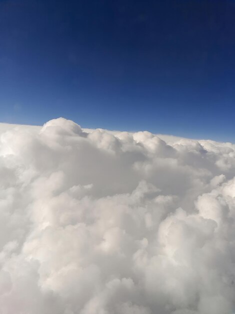 Vue rapprochée des nuages depuis une fenêtre d'avion contre un ciel bleu