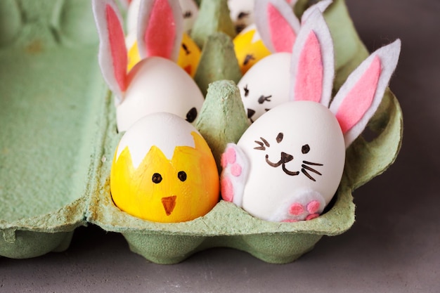 Vue rapprochée des oeufs décoratifs de pâques lapins et poussins dans un emballage en carton