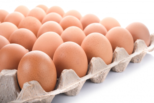 Vue rapprochée des œufs de poule crus en boîte sur fond blanc