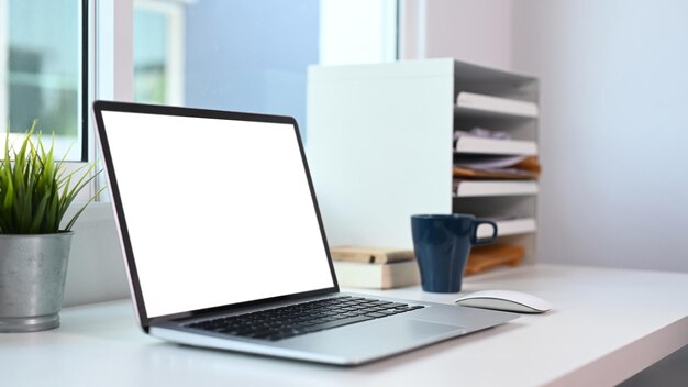 Vue rapprochée d'un ordinateur portable avec écran blanc sur un bureau moderne.