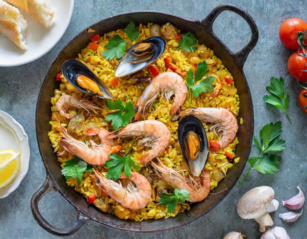 Photo vue rapprochée d'une paella espagnole traditionnelle dans une casserole sur une table de cuisine avec de la mer prête à manger