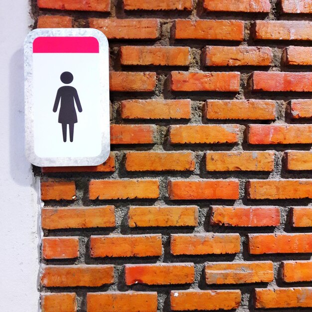 Photo vue rapprochée d'un panneau de toilette sur un mur de brique