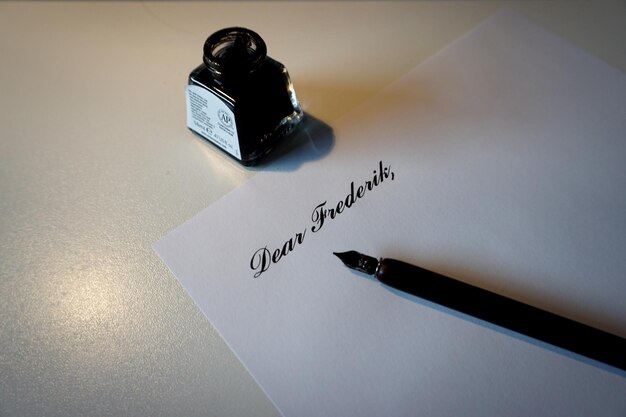 Photo vue rapprochée d'un papier avec un stylo plume et une bouteille d'encre sur la table