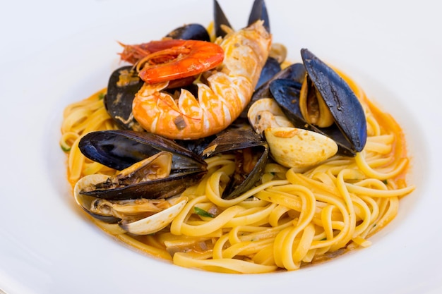 Vue rapprochée des pâtes avec des crevettes et des palourdes servies dans une assiette blanche