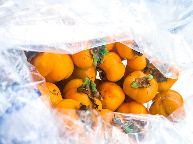 Photo vue rapprochée de persimmons en plastique à vendre au stand du marché