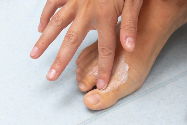 Vue rapprochée d'une personne caucasienne massant de la crème hydratante dans le haut du concept de santé et de dermatologie de la peau des pieds nus et des orteils