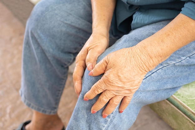 Photo vue rapprochée de personnes âgées assises à genoux avec les mains touchant ou saisissant en raison de la douleur et de la douleur