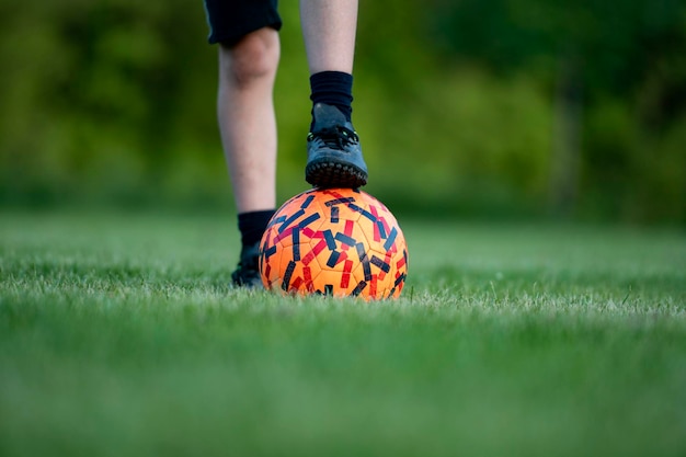 Vue rapprochée d'un pied d'enfant dans une chaussure de football sur le dessus d'un ballon de football