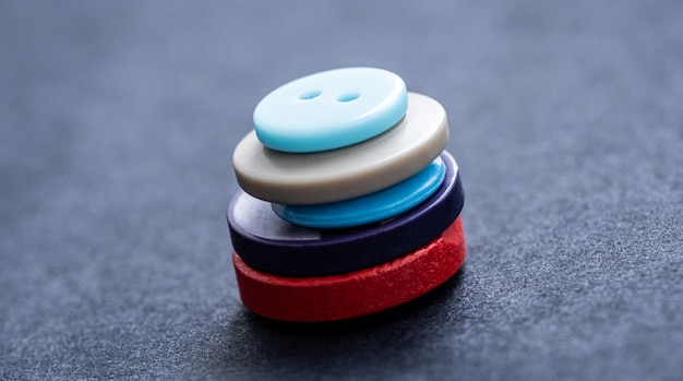 Vue rapprochée de la pile de boutons de couture colorés sur gris