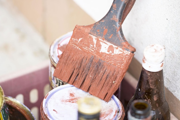 Vue rapprochée d'un pinceau avec des boîtes de peinture près du mur